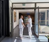 Twee verpleegkundigen lopen door de gang en kijken om